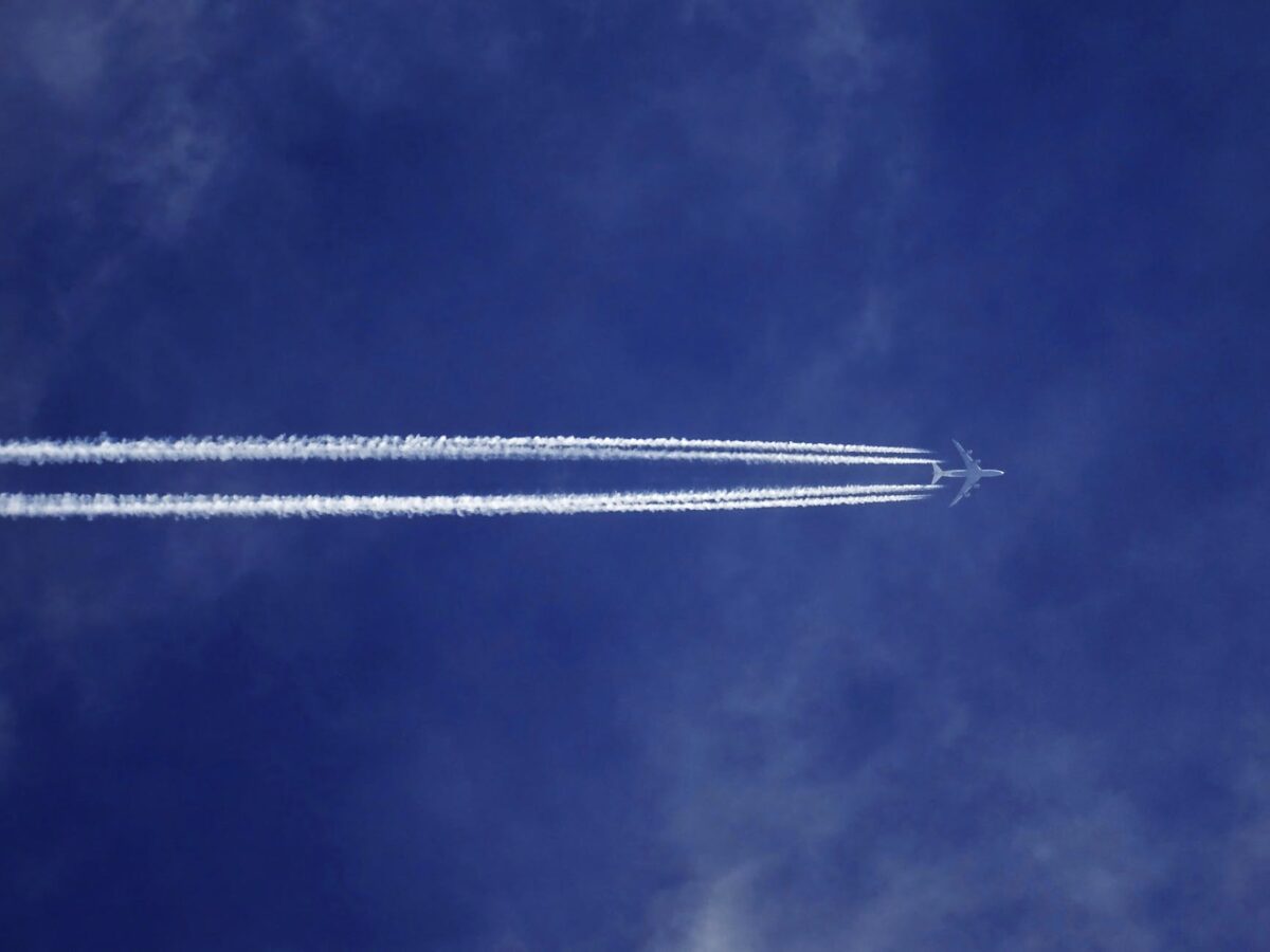 bottom view of plane with contrail
